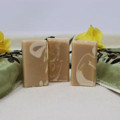 Picture of By the Sea Soap Shoppe Great Goat Soap Mini Soaps standing between green flowered towels with yellow roses in the background. Soap ingredients include goat milk and a 