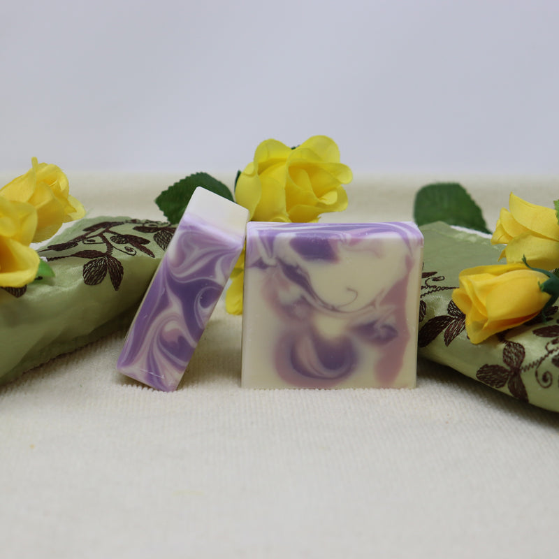 By the Sea Soap Shoppe bar of soap called "Rose and Lavender". Picture shows two bars of soap that are white with mauve and purple swirls. Soap includes Rose Essential Oil and Lavender Essential Oil. Vegan, all-natural ingredients, handmade in Prince Edward Island. $7.00 each